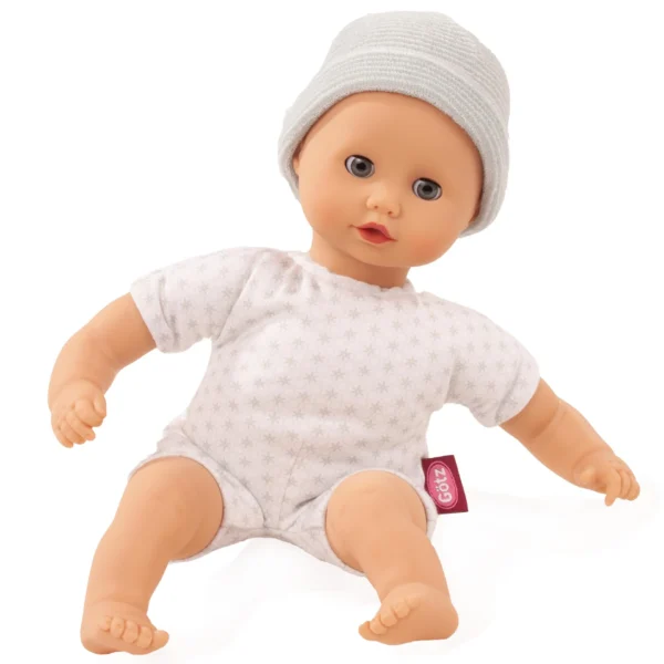 Babypop met wit gebreide muts en rompertje met sterrenprint op witte achtergrond