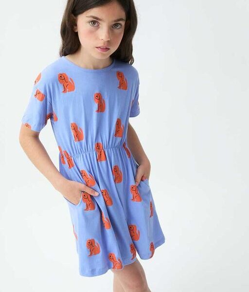 Meisje draagt blauw jurkje met oranje hondenprint en elastische taille met zijzakken