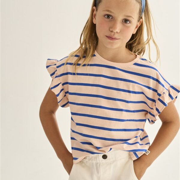 Meisje met blauw gestreept shirt, witte broek en blauwe haarband tegen lichte achtergrond