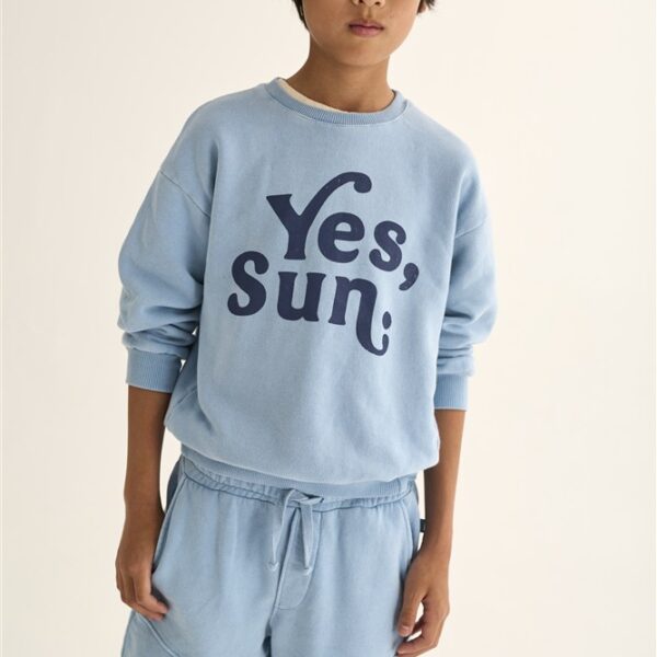 Jongen in lichtblauwe sweater met tekst Yes Sun en bijpassende shorts voor witte achtergrond
