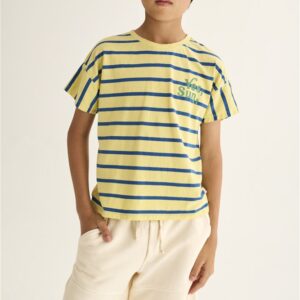 Jongen in geel gestreept t-shirt met blauwe strepen en beige short voor witte achtergrond